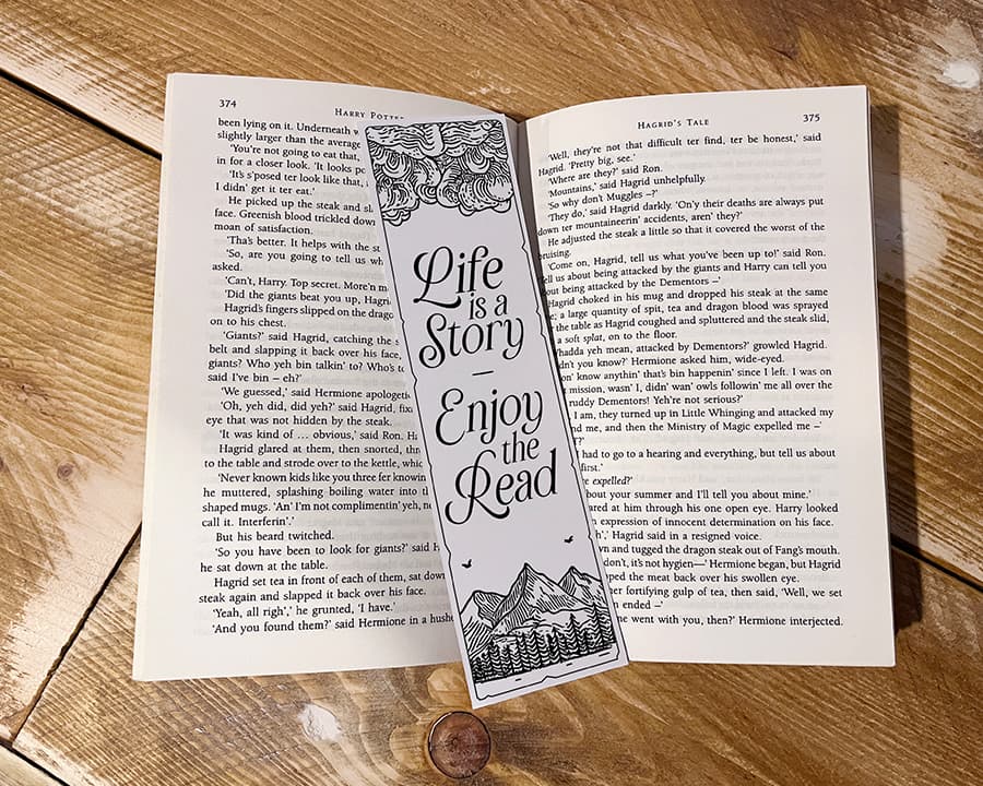 An open book with a decorative bookmark resting on its pages, featuring the quote 'Life is a story, enjoy the read.'