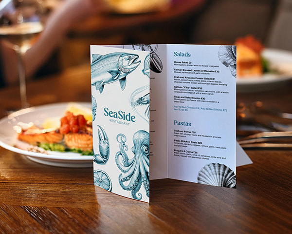 Folded menu with hand-drawn sea creature illustrations on a wooden table, in a rustic seafood restaurant, adding to the coastal dining atmosphere.