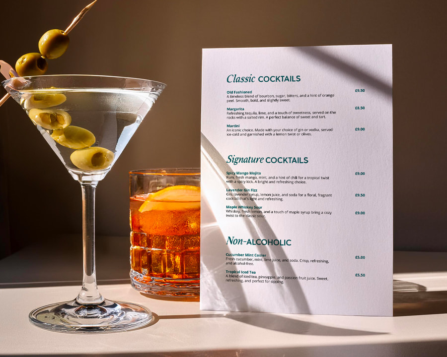 Printed drinks menu displayed beside vibrant cocktails, showcasing high-quality menu printing ideal for bars and restaurants.